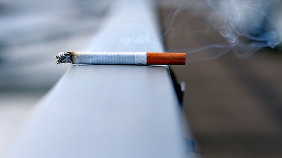 angezündete Zigarette liegt auf Geländer