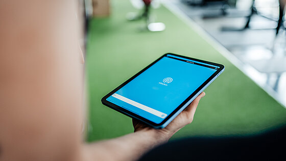 Arm mit iPad, zeigt Startbildschirm der clockin App